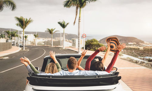 Rear view of people sitting in car on road against sky