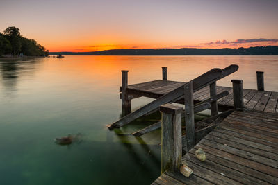 Pier over lake against sky during sunset