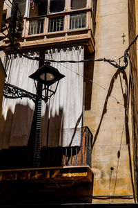 Low angle view of electric lamp on old building