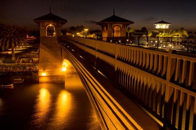 Illuminated bridge over river against sky at night