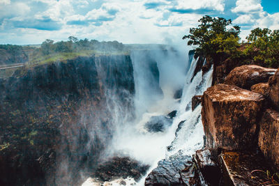 Scenic view of waterfall against sky