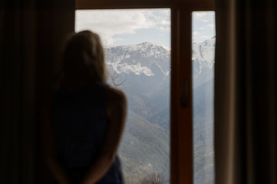 Rear view of woman looking through window