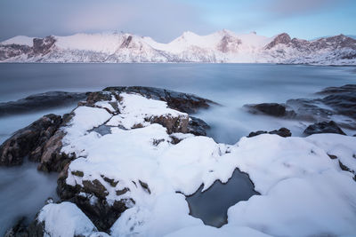 Scenic view of sea and snowcapped mountains against sky