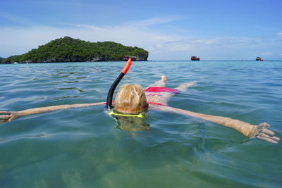 Woman swimming in sea against blue sky