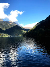 Scenic view of lake and mountains against blue sky