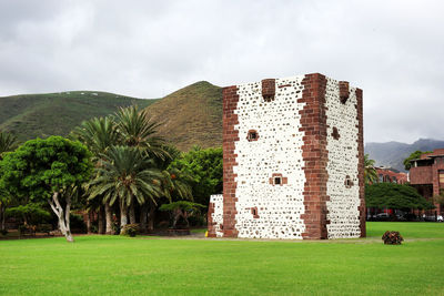 Built structure on field by mountain against cloudy sky