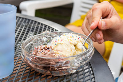 Close-up of hand holding ice cream in bowl