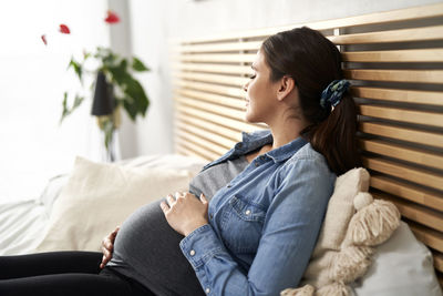 Side view of pregnant mother resting on bed