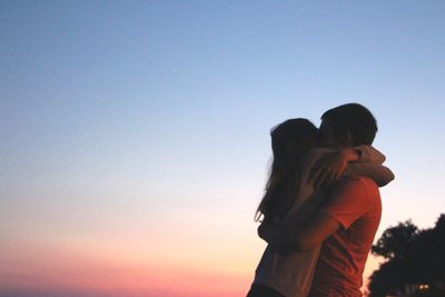 Couple hugging against clear sky during sunset