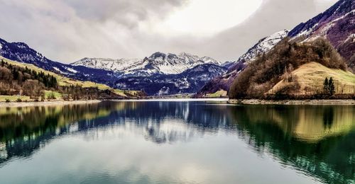 Scenic view of lake by snowcapped mountains against sky