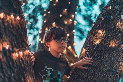 Full length of boy looking at tree trunk
