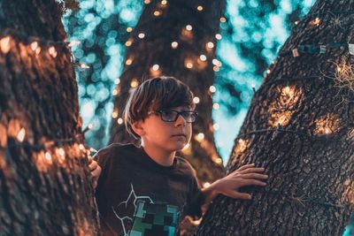 Full length of boy looking at tree trunk