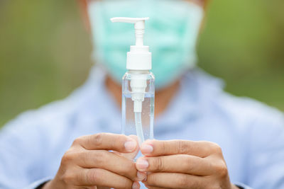 Close-up of hand holding bottle against blurred background