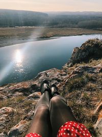 Low section of woman sitting at lakeshore