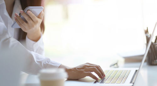 Midsection of man using mobile phone on table