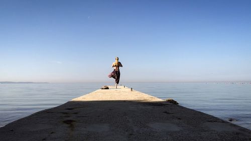 Rear view of man on beach against clear sky