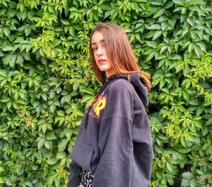 Young woman standing against plants