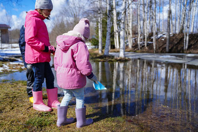 Rear view of women standing by pink lake against trees