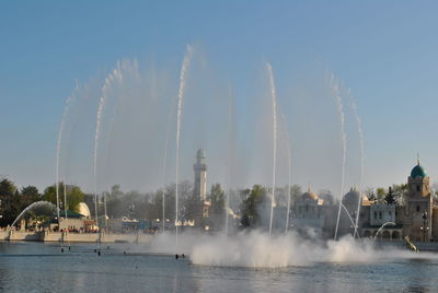 Panoramic view of fountain and palm trees against sky