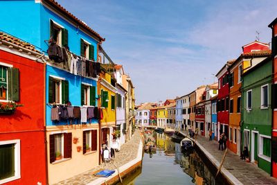 Canal amidst houses against sky in city