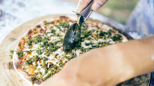 Close-up of hand holding pizza on table