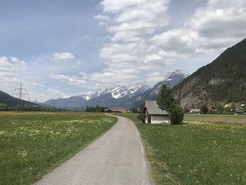 Road amidst field against sky