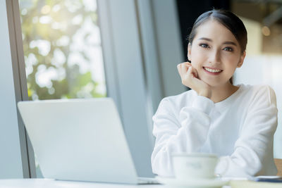 Portrait of smiling young woman using mobile phone