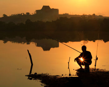 Silhouette man fishing at lake