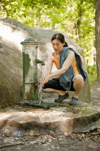 Woman washing her hands at water pump in fontainebleau forest