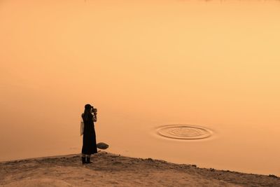 Man standing against orange sky