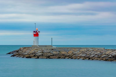 Lighthouse by sea against sky