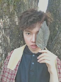 Portrait of boy standing against tree