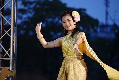 Smiling young woman against sky at night