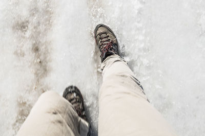 Low section of mid adult man walking on snow covered field