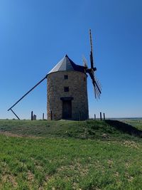 Traditional windmill on field against clear blue sky