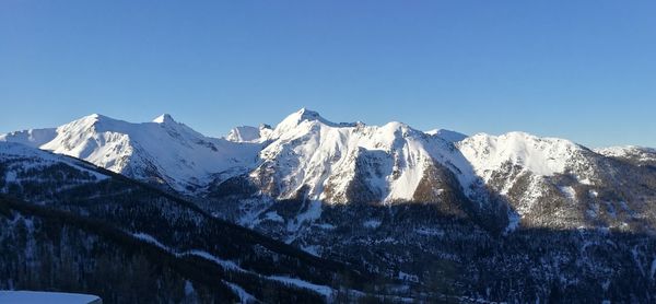 Scenic view of snowcapped mountains against clear blue sky