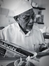 Senior man reading newspaper while sitting at table