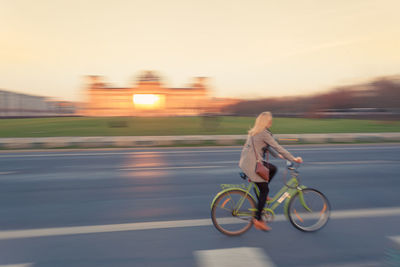 Woman cycling on road by illuminated reichstag building