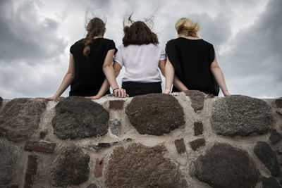 Rear view of people on rock against sky