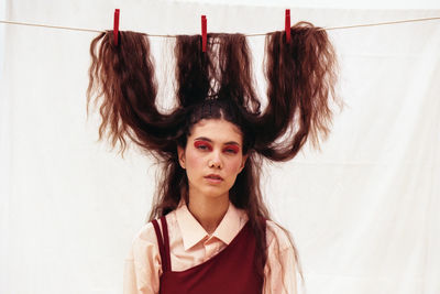 Portrait of young woman with long hair tied up on clothesline