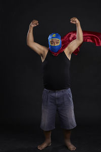 Portrait of man in costume flexing muscles against black background