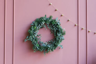 Beautiful stylish christmas wreath on the pink wall in the house