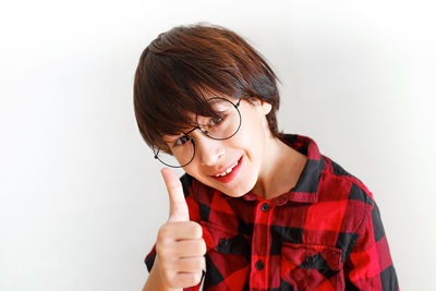 Portrait of young woman holding eyeglasses against white background