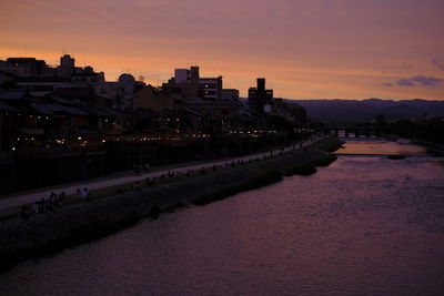 River amidst buildings against sky at sunset
