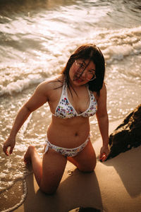 Portrait of young woman in bikini standing at beach