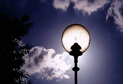 Low angle view of illuminated street light against cloudy sky