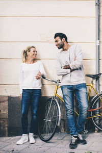 Friends communicating while standing by bicycle on sidewalk