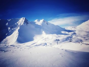 Scenic view of snowcapped mountains against blue sky