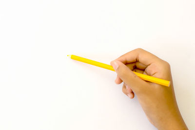 Close-up of hand holding pencils against white background