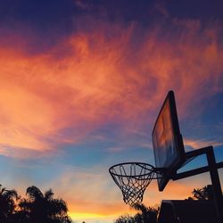 Low angle view of basketball hoop against cloudy sky during sunset